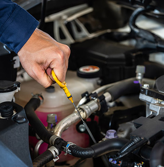 hand of technician checking the oil level on dipstick in car engine